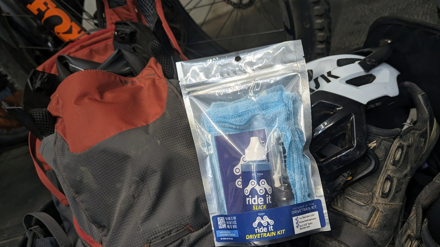Ride It Drivetrain Kit by SCC Tech, featuring a complete bike maintenance solution. The packaging displays the Ride It brand logo and includes products like Ride It Slick, Ride It Clean, Ride It Smooth, and Ride It Flow. The kit contains 2 fl oz (59 ml) bottle of Ride It Slick drivetrain treatment, precision needle applicators, and a microfiber towel. The label highlights the kit’s focus on enhancing bike performance and protection, with bold text encouraging less time working on it and more time riding it