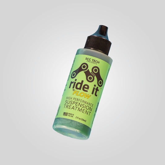 2 fl oz bottle of Ride It w/ Flow High-Performance Suspension Treatment by SCC Tech. The green label features a chain link graphic and highlights the product’s use for enhancing bike suspension performance. Made in the USA, this specialized formula reduces friction and protects seals and stanchions, ensuring a smoother and more responsive ride
