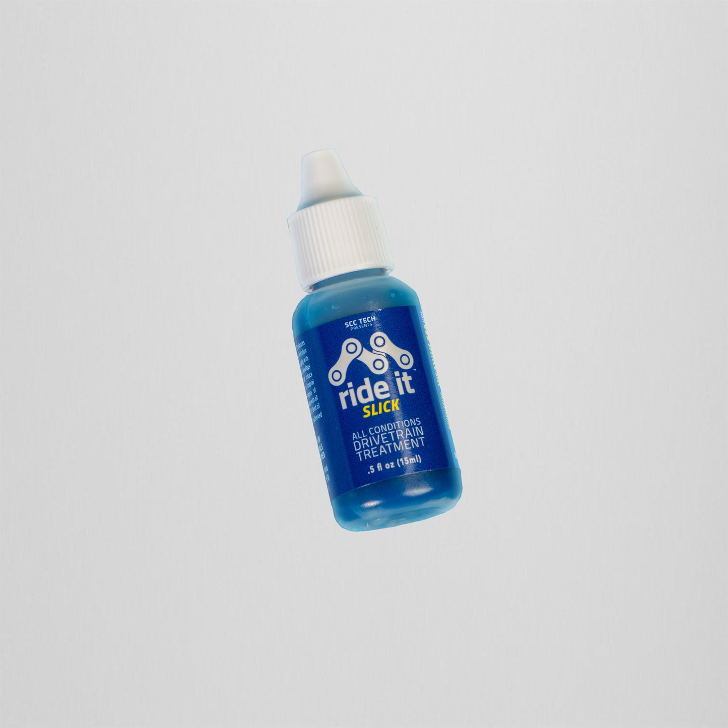 alt txt: Small blue bottle of Ride It Slick all-conditions drivetrain treatment for bicycles. The 0.5 fl oz (15 ml) bottle has a white cap and features a blue label with white and yellow text. The label includes a chain graphic and states 'SCC Tech' and 'Ride It Slick' in bold. The product is designed to improve bicycle drivetrain performance in various weather conditions