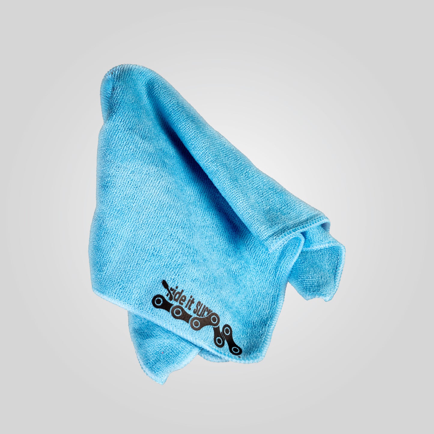 Blue microfiber towel with a printed black bicycle chain logo, designed for cleaning and maintaining bicycles. The soft, high-quality microfiber material is ideal for wiping down bike frames, components, and drivetrains, helping to remove dirt, grime, and excess lubricant during maintenance. This towel is part of the Ride It bike care kit, offering a gentle yet effective cleaning solution.